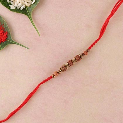 Rudraksha and brass beads rakhi in red spiral woven thread