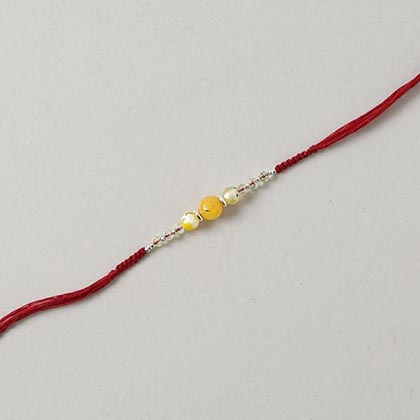 Yellow agate and yellow crystal rakhi in flat woven burgundy thread