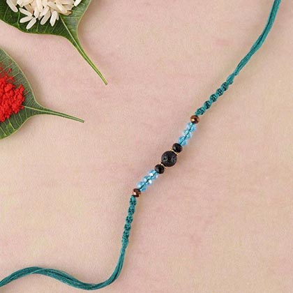 Lava and blue crystal rakhi in teal spiral woven thread