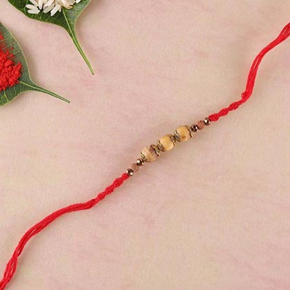 Sandalwood and brass bead rakhi in red thread