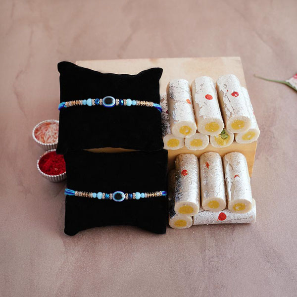 Two Evil Eye Rakhis with kaju Roll Sweets